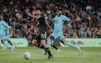 LAFC’s Carlos Vela went up the field with the ball with Minnesota United’s Oniel Fisher in pursuit Sunday night in Los Angeles.
