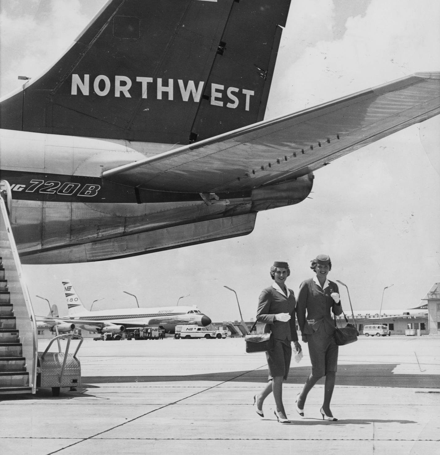 NWA stewardesses Darlene Jevne (L) and Virginia Dwight walk from their 720B fan-jet airliner after arrival at Miami from the Midwest, ready for a layover enjoying the sights and activities of the Miami area. November, 1962 Northwest airlines historical.