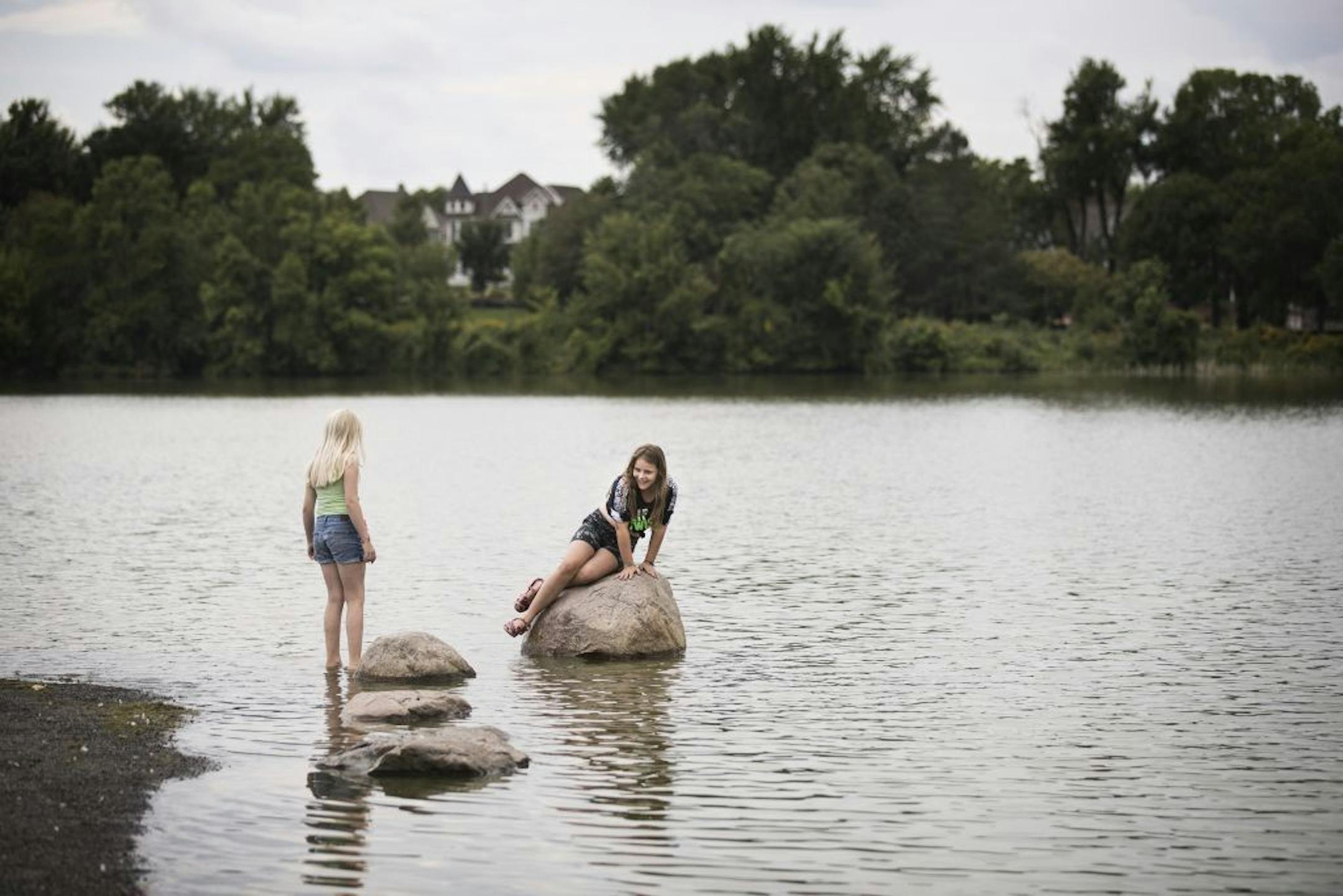 Friends Leni Haarbusch, 10, and Emma Theis, 10, both of St. Paul, climb rocks near the shore of Como Lake.