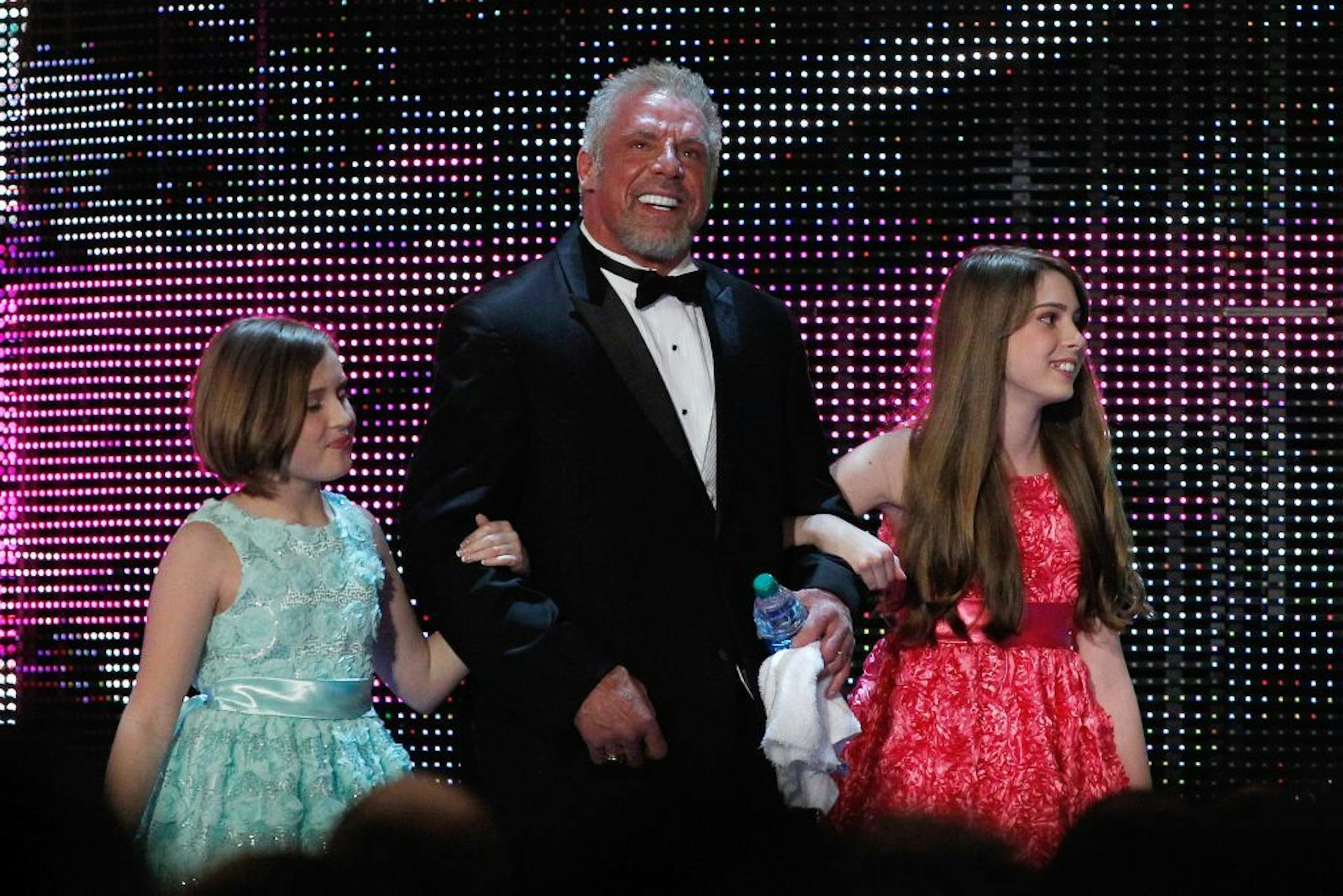 FILE - In this April 5, 2014 file photo provided by the WWE, James Hellwig, aka The Ultimate Warrior, is escorted by his daughters to the stage during the WWE Hall of Fame Induction at the Smoothie King Center in New Orleans.