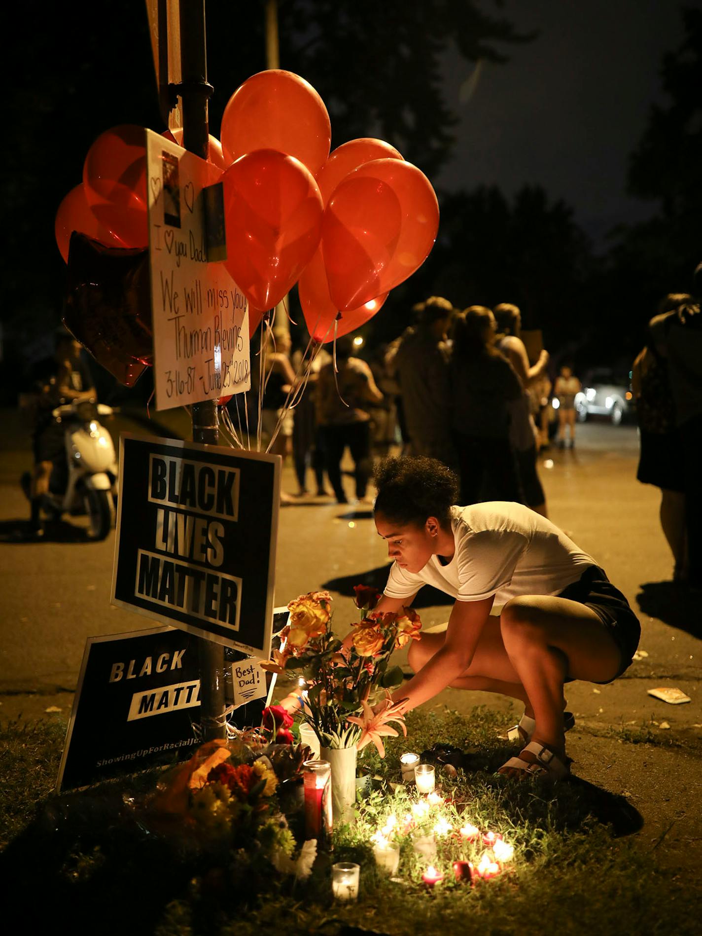 A.J. Cardenas relit some of the candles that had gone out at a memorial to Thurman Blevins at the corner of 47th and Camden Ave. N. as the vigil ended.