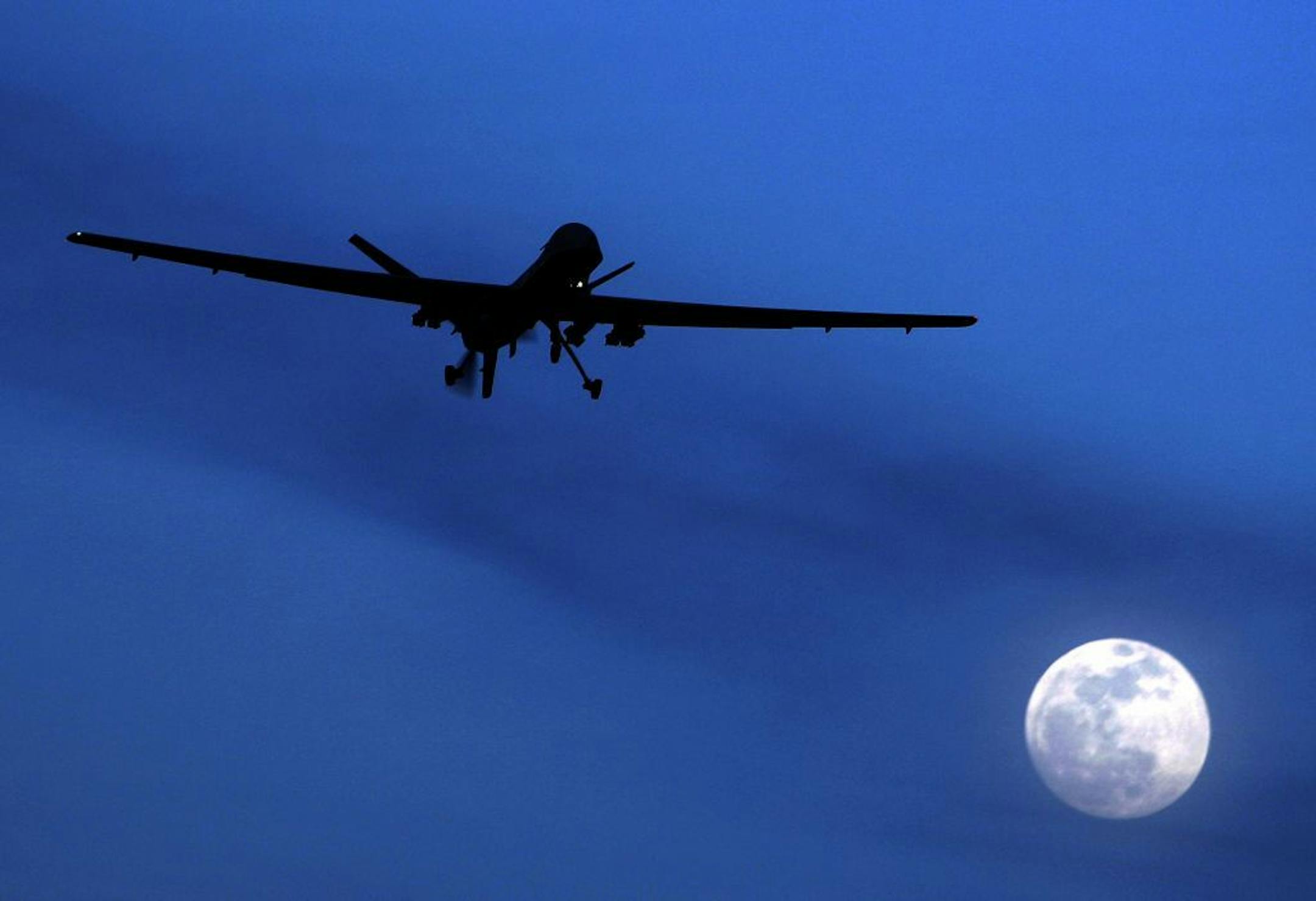 FILE - This Sunday, Jan. 31, 2010 file photo shows a U.S. Predator drone as it flies over the moon above Kandahar Air Field, southern Afghanistan. A U.S. drone fired a pair of missiles that hit a vehicle in northwestern Pakistan, near the Afghan border killing three suspected militants, in Datta Khel village of North Waziristan tribal region at about midnight Thursday, two intelligence officials said.