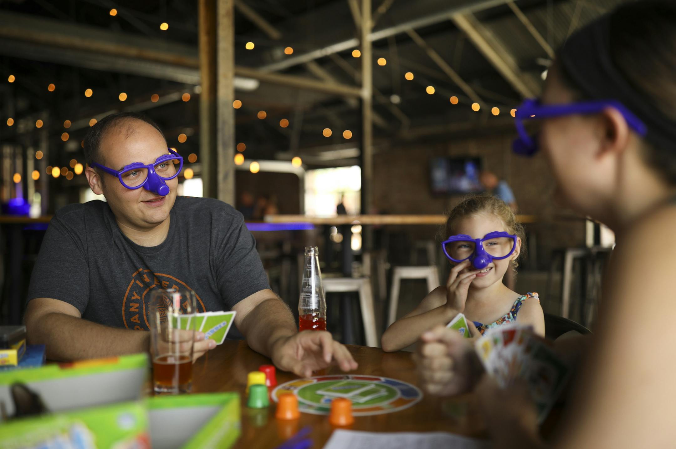 Abbie Symoniak, 6, went on an adventure with her aunt and uncle, Anna and Tom Brudzinski of Richfield, to Lake Monster Brewing Co. in St. Paul, where they played board games Sunday afternoon. They are playing the game "Fibber" in this photo, which requires player to wear the silly glasses. ] JEFF WHEELER ï jeff.wheeler@startribune.com Beer used to be sold in bars, where children weren't allowed. Now beer flows freely in breweries, which have become family friendly. At Lake Monster Brewing C