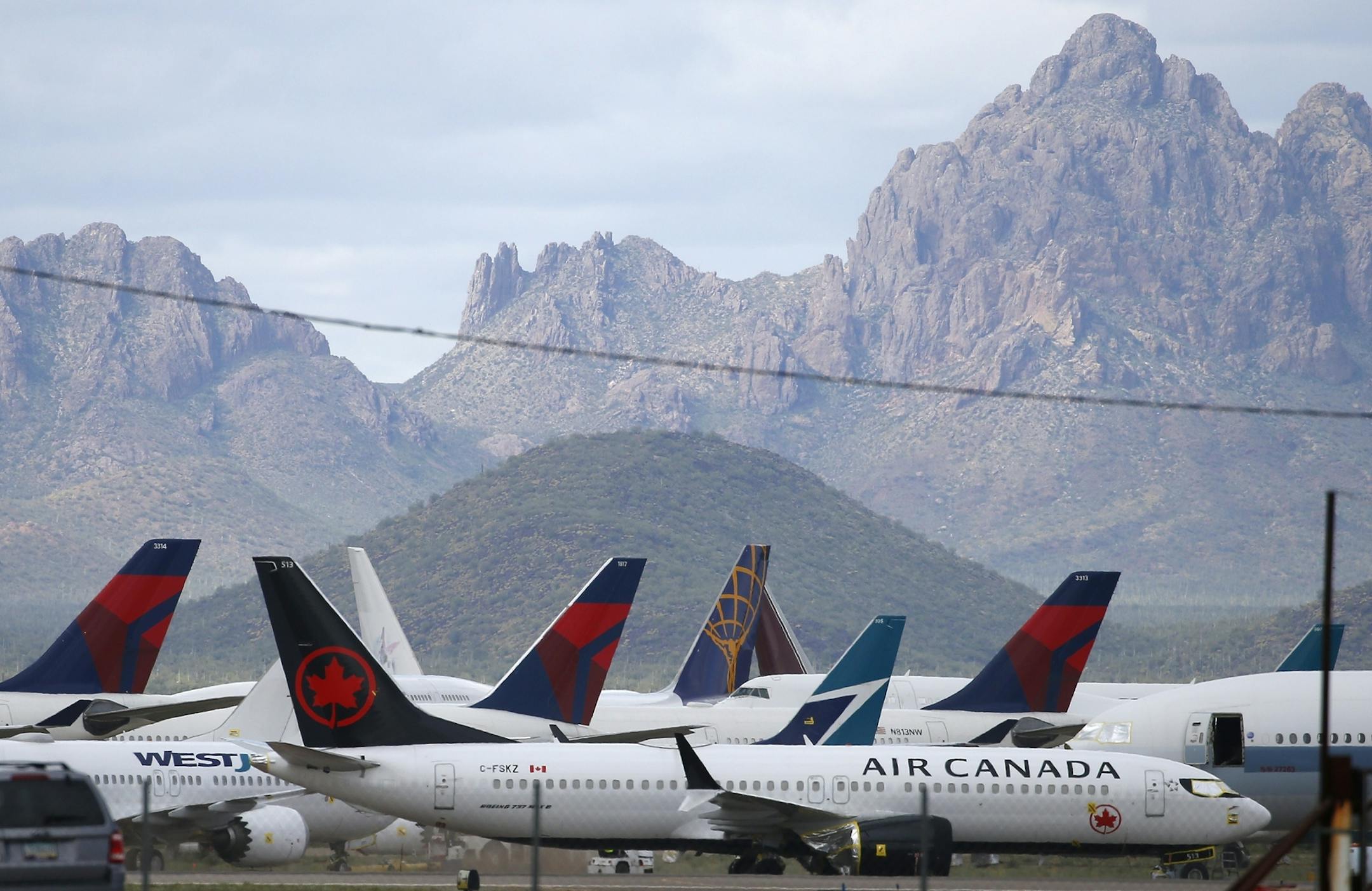 In this Wednesday, March 18, 2020 photo, several passenger airplanes sit parked at Pinal Airpark in Red Rock, Ariz., as many passenger planes are being kept at the facility while airlines cut back on service due to the coronavirus. (AP Photo/Ross D. Franklin)