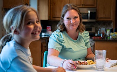 Ellie, 7, left, laughs as she eats dinner with her mother, Meta Getman, at their home in Eden Prairie on April 24. Meta, a fertility coach, gave birth