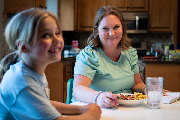 Ellie, 7, eats dinner with her mother, Meta Getman, at their home in Eden Prairie. Meta, a fertility coach, gave birth to Ellie and her twin, Addie, t