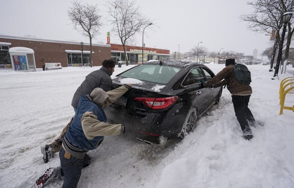 A group of bystanders helped a car get out of its parking spot Wednesday on Central Avenue in Minneapolis. A total of 8.9 inches fell at the airport.
