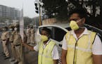 Volunteers and policemen wear pollution masks and stand at a busy crossing with the banner saying obey odd and even, remove pollution, in New Delhi, I