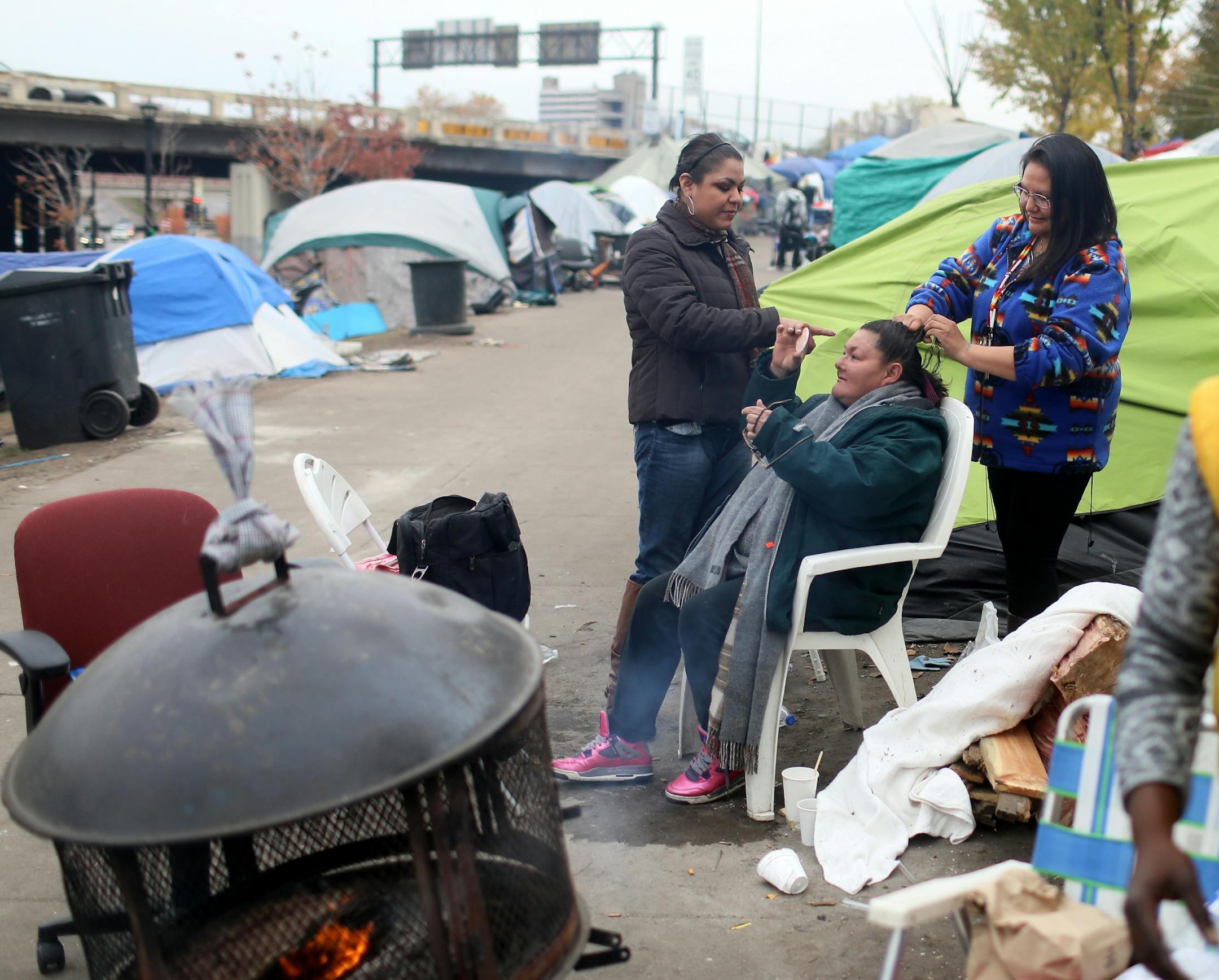 This week, after months of living at a crowded homeless camp, Mike and Ellen Eagletail and their three children finally moved into a place of their own. They are among a small but growing number of people at a south Minneapolis homeless camp who are starting to find housing. Here, Ellen Eagletail braids the hair of encampment resident Nancy Thunder, seated, as fellow resident Kathleen Jackson does makeup on Thunder. The women say it is important to feel good about yourself, regardless of where t