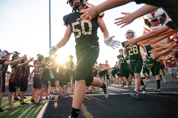 Lakeville South players run out of the tunnel between lines of youth football players before their season opener against Wayzata Friday, Sep. 01, 2023