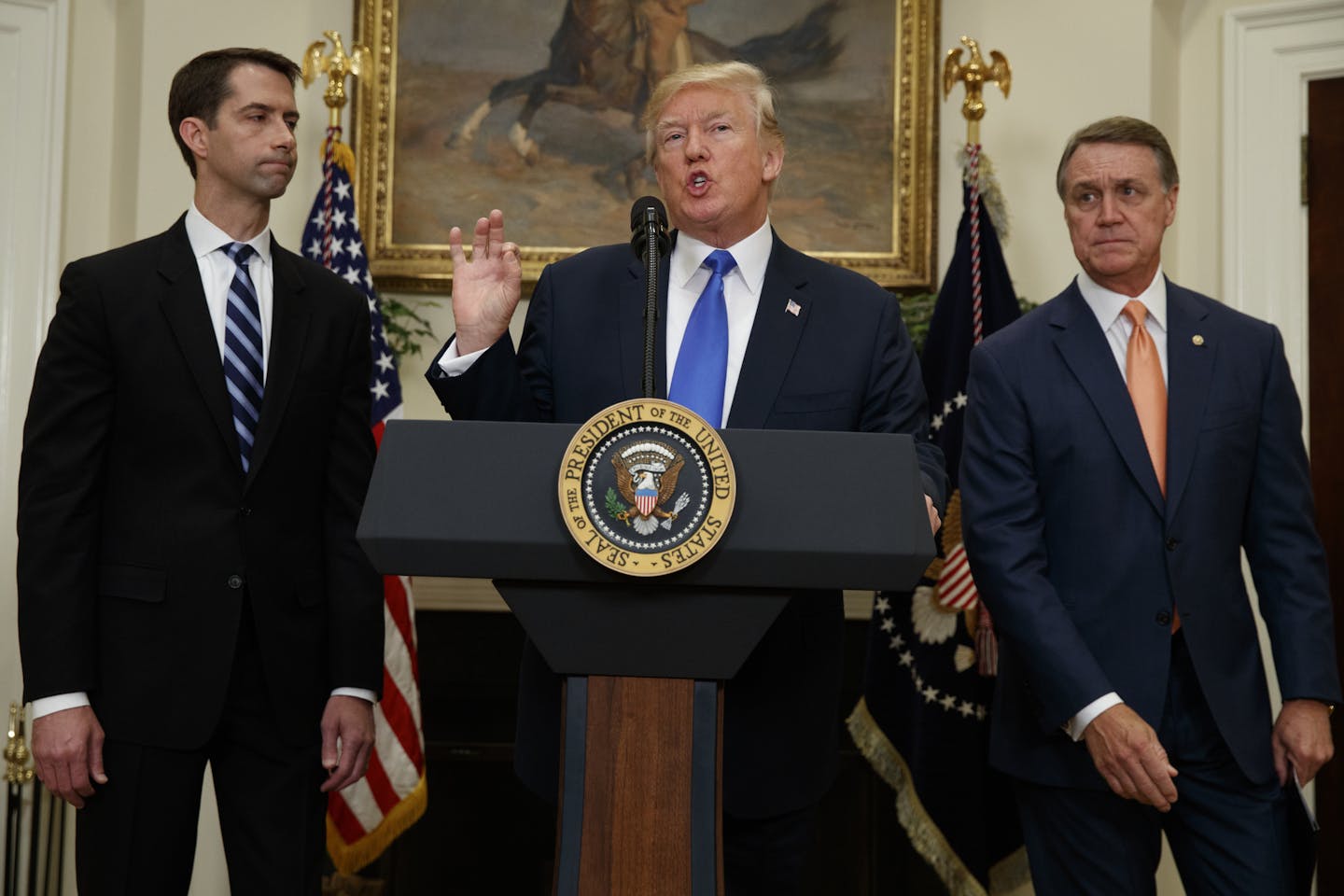 President Donald Trump, flanked by Sen. Tom Cotton, R- Ark., left, and Sen. David Perdue, R-Ga., speaks in the Roosevelt Room of the White House in Washington, Wednesday, Aug. 2, 2017, during the unveiling of legislation that would place new limits on legal immigration. (AP Photo/Evan Vucci)