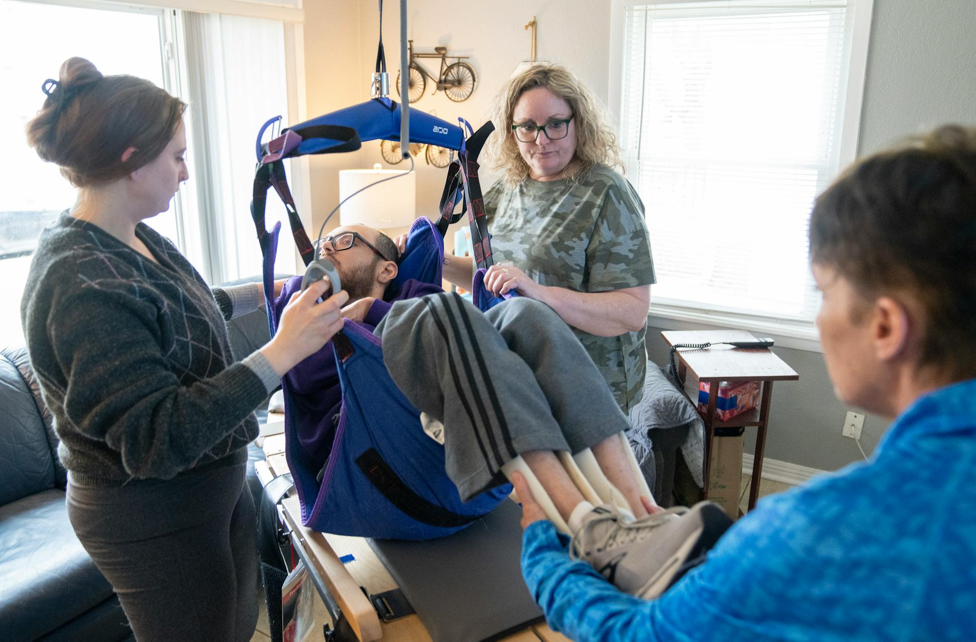 Ashley Topp, Kathy Ware and Lori McCoy guide Kylen's motorized lift during a physical therapy session.