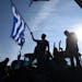 A protesting farmer waves a Greek flag during a rally in the northern Greek city of Thessaloniki on Thursday, Jan. 28, 2016. Greek farmers continued h