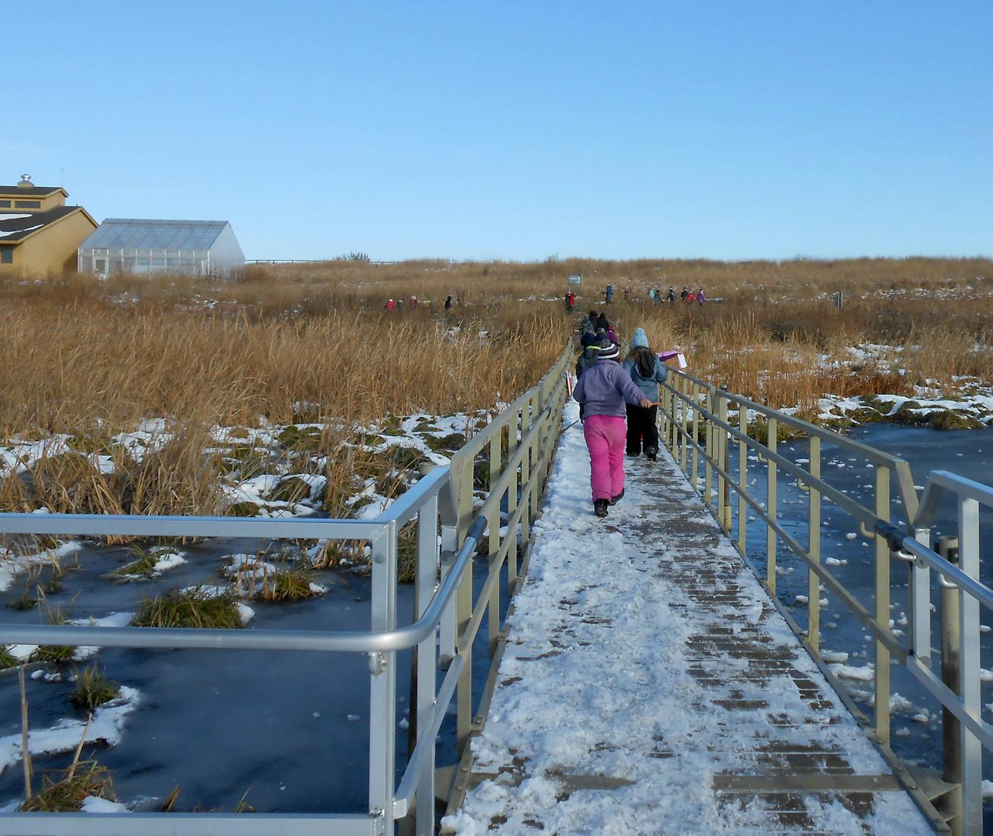 The education wing and greenhouse of the Prairie Wetlands Learning Center rise beyond a footbridge over Mallard Marsh in Fergus Falls, Minn. Joanne Ryan/USFWS