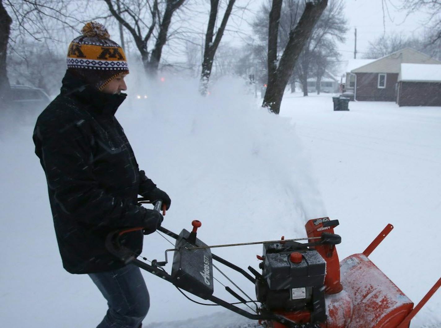 Brian Baxter uses a snowblower to clear his driveway as it snows Monday, Dec. 28, 2015, on Seventh Street Northeast in Rochester, Minn.