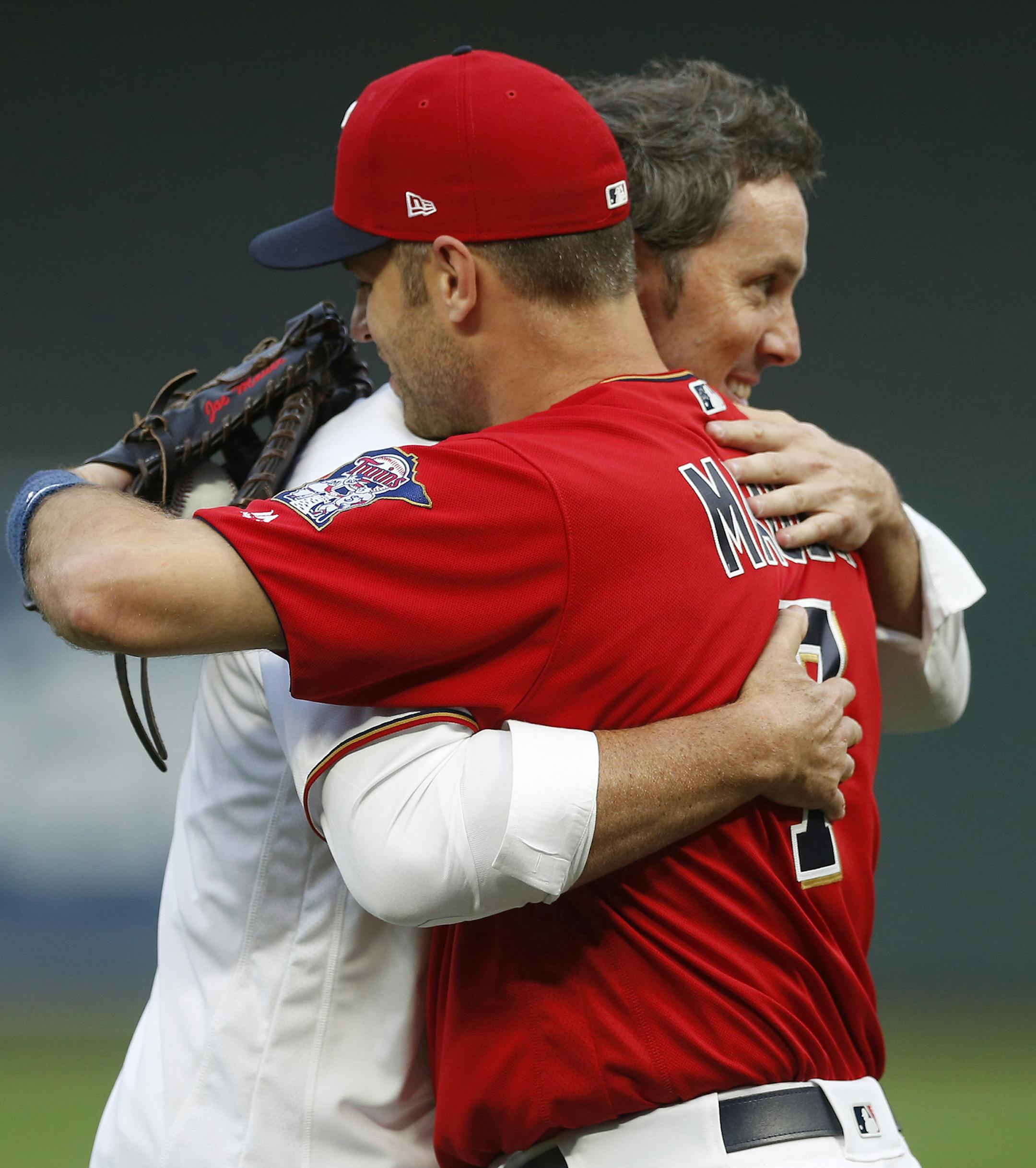 Former Minnesota Twins pitcher Joe Nathan, right, and Twins' Joe Mauer hug after Mauer caught the ceremonial first pitch shortly after Nathan, the team's closer, signed a one-day contract to announce his retirement from baseball, prior to the Twins' game against the Kansas City Royals on Friday, Sept, 1, 2017, in Minneapolis. (AP Photo/Jim Mone)