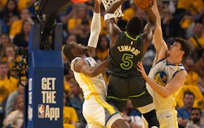 Timberwolves guard Anthony Edwards (5) puts up a shot between the defense of Golden State Warriors forward Jonathan Kuminga (00) and center Quinten Po