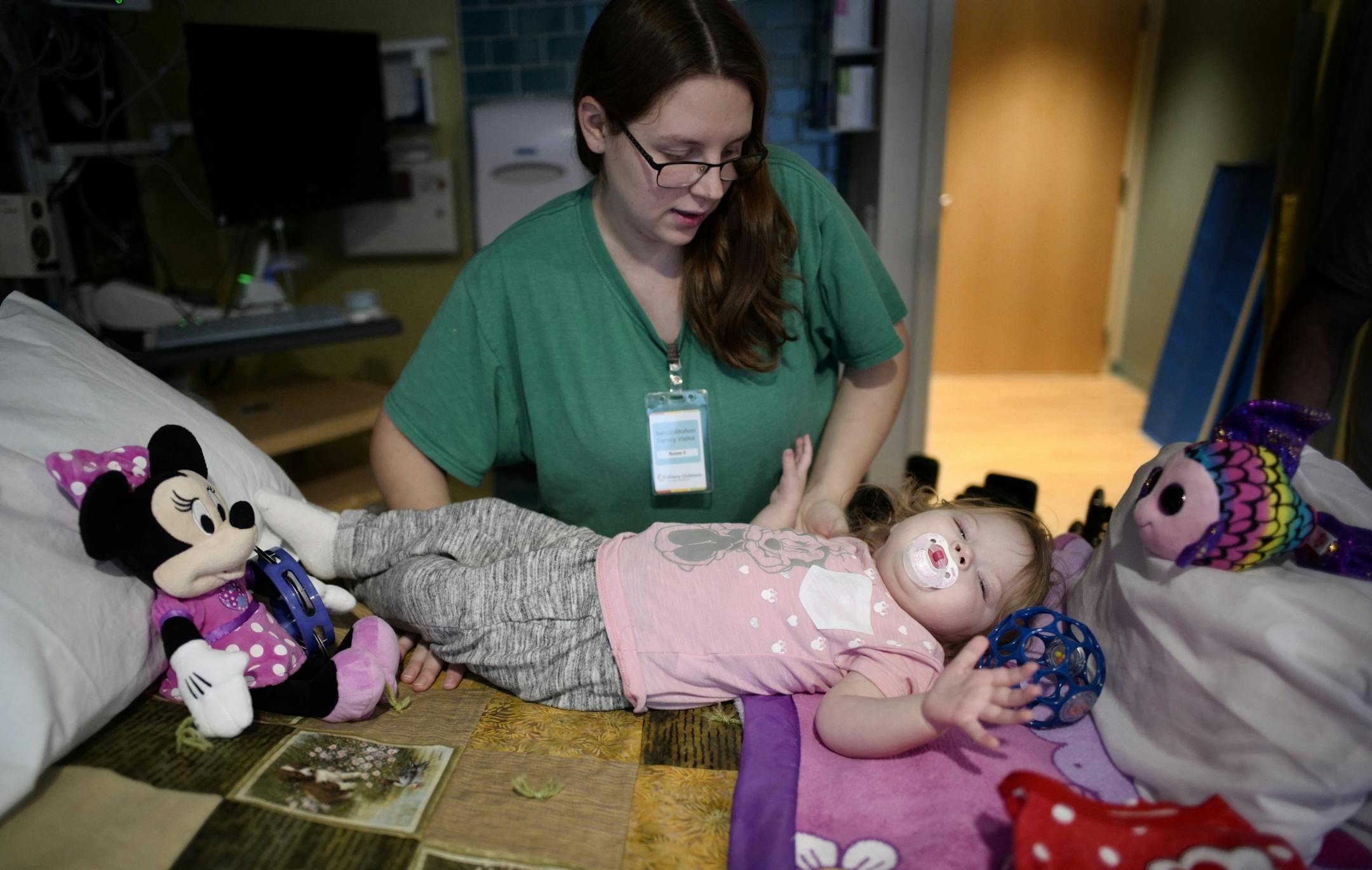 Haley Long helps place her daughter Aria into her hospital bed. She has partial paralysis in her left leg caused by AFM.