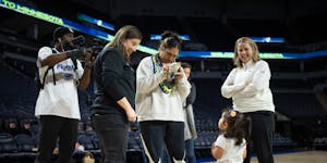 Alissa Pili signs a stuffed animal for fan Tala Hubbard, 2, while standing with Carley Knox, Lynx president of business operations, and head coach Che