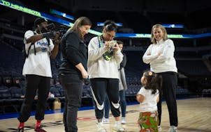 Alissa Pili signs a stuffed animal for fan Tala Hubbard, 2, while standing with Carley Knox, Lynx president of business operations, and head coach Che