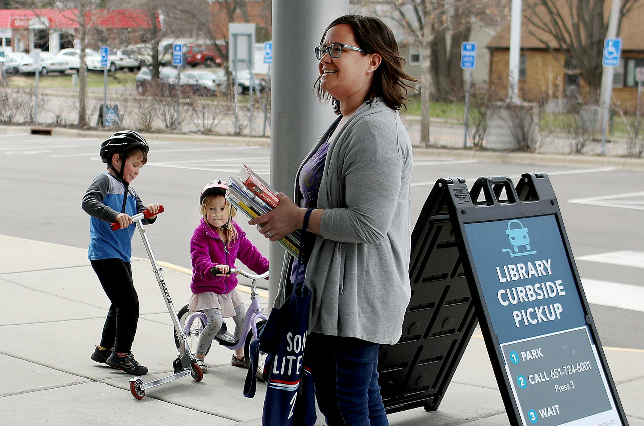 Lis Moriarty and her two children, Brenna, 4, and Liam, 5, walked from their home to the to the Ramsey County Library-Roseville, for curbside pickup and drop-off Thursday, April 23, 2020, in Roseville, MN.] DAVID JOLES • david.joles@startribune.com No customer has stepped foot in a Ramsey County Library in a month but patrons are still checking out more than 1,000 books, magazines and DVDS each day thanks to the county's curbside pick-up program. While some counties quickly furloughed lib