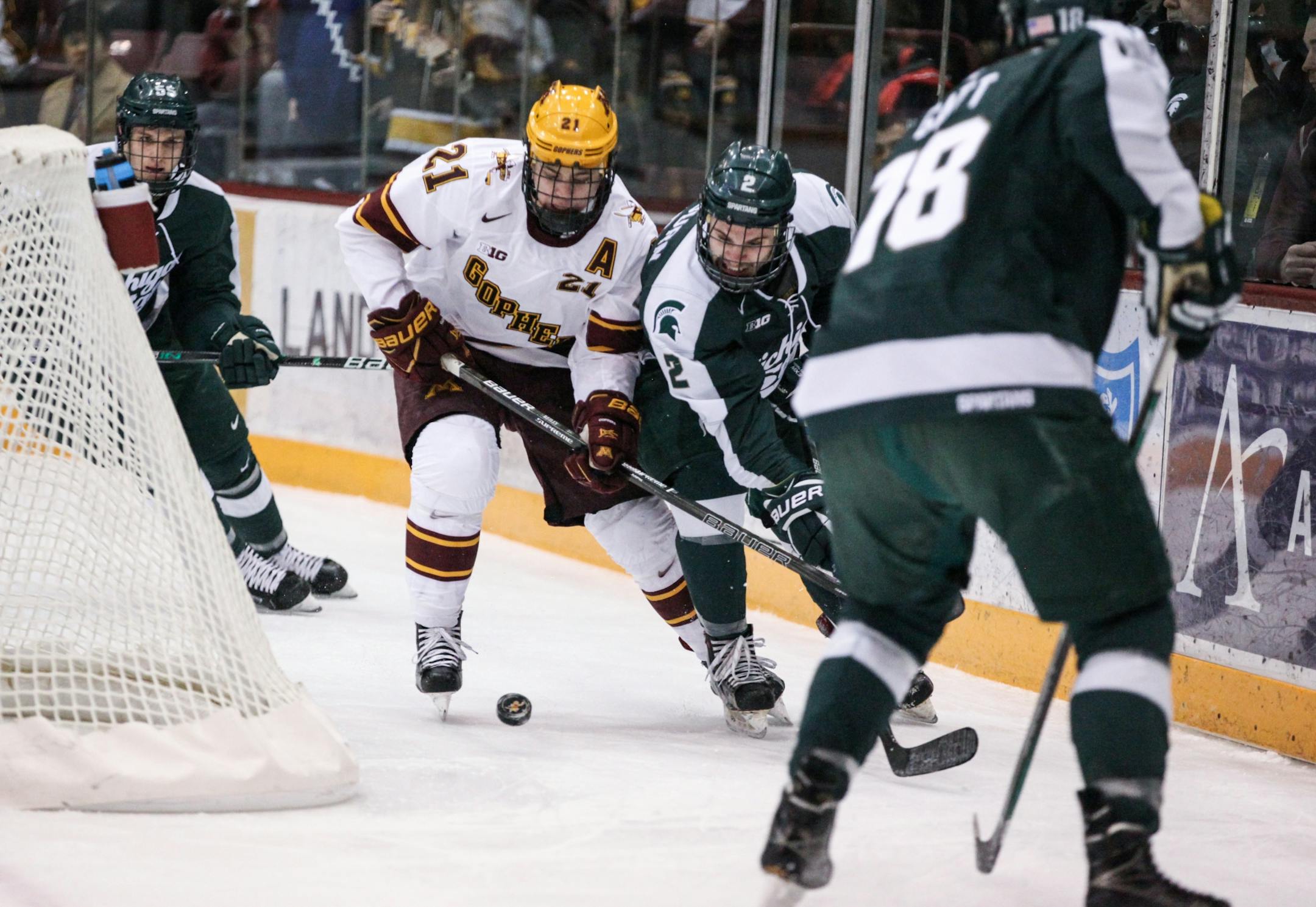 Minnesota Gophers� Connor Reilly (21) and Michigan State Spartans� Zach Osburn (2) chase the puck in the first period.