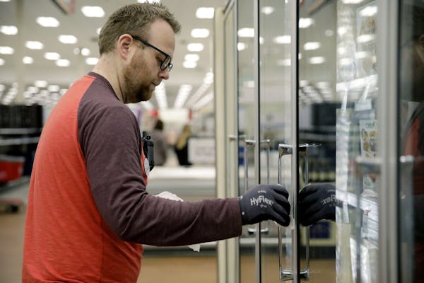 A Target employee in Tulsa cleans door handles. Target has stepped up safety measures at its stores. (Mike Simons/Tulsa World via AP)
