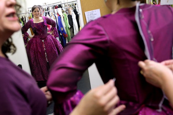 Opera singer Heather Johnson tries on a dress during a costume fitting with shop owner Ellen Roeder, left, and Minnesota Opera draper Chris Bur at Tul
