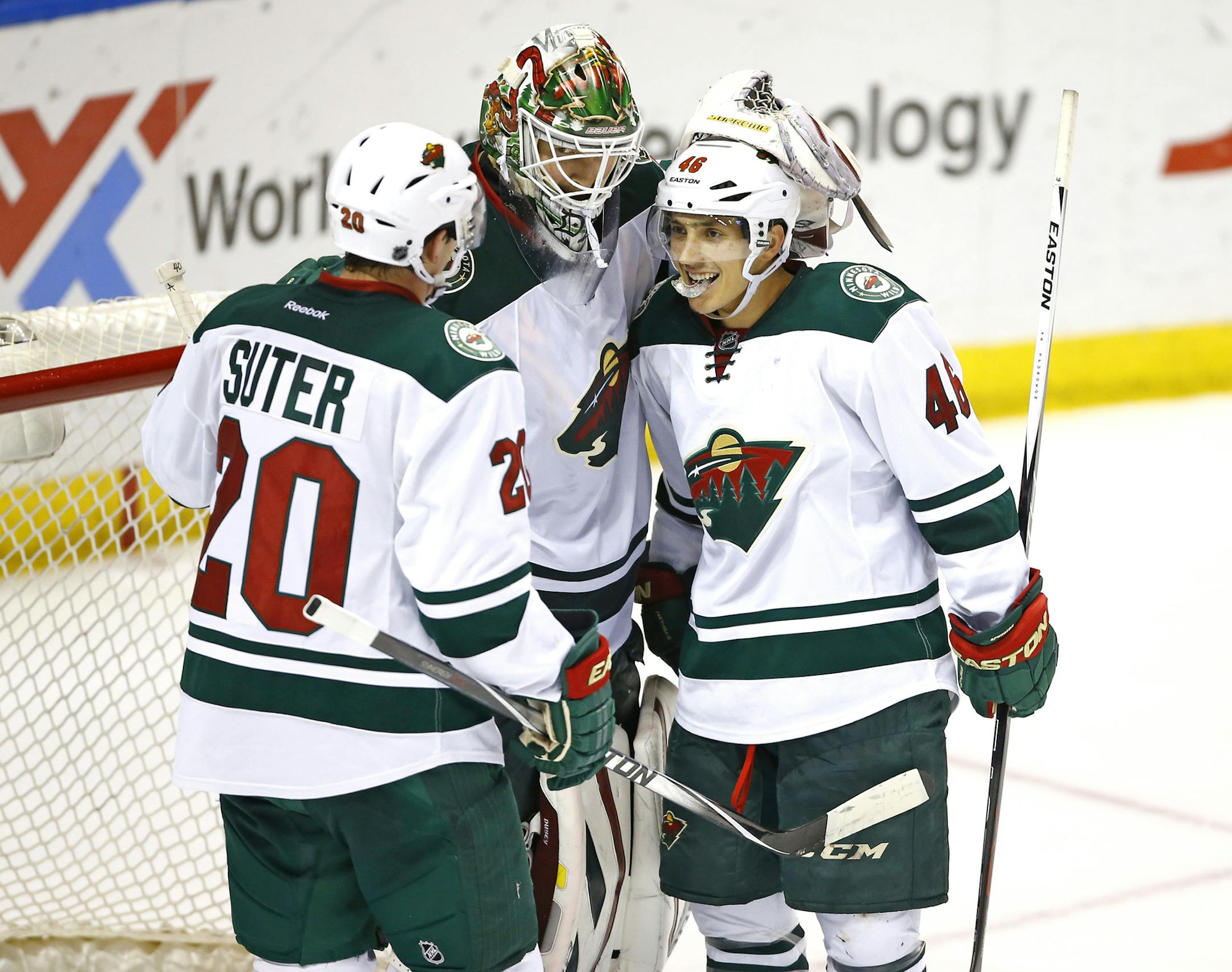 Minnesota Wild goalie Devan Dubnyk, center, is congratulated by teammates Ryan Suter, left, and Jared Spurgeon, right, at the completion of an NHL hockey game against the St. Louis Blues, Saturday, March 14, 2015, in St. Louis. Minnesota won the game 3-1. (AP Photo/Billy Hurst) ORG XMIT: MOBH118