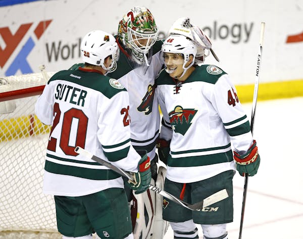 Minnesota Wild goalie Devan Dubnyk, center, is congratulated by teammates Ryan Suter, left, and Jared Spurgeon, right, at the completion of an NHL hoc