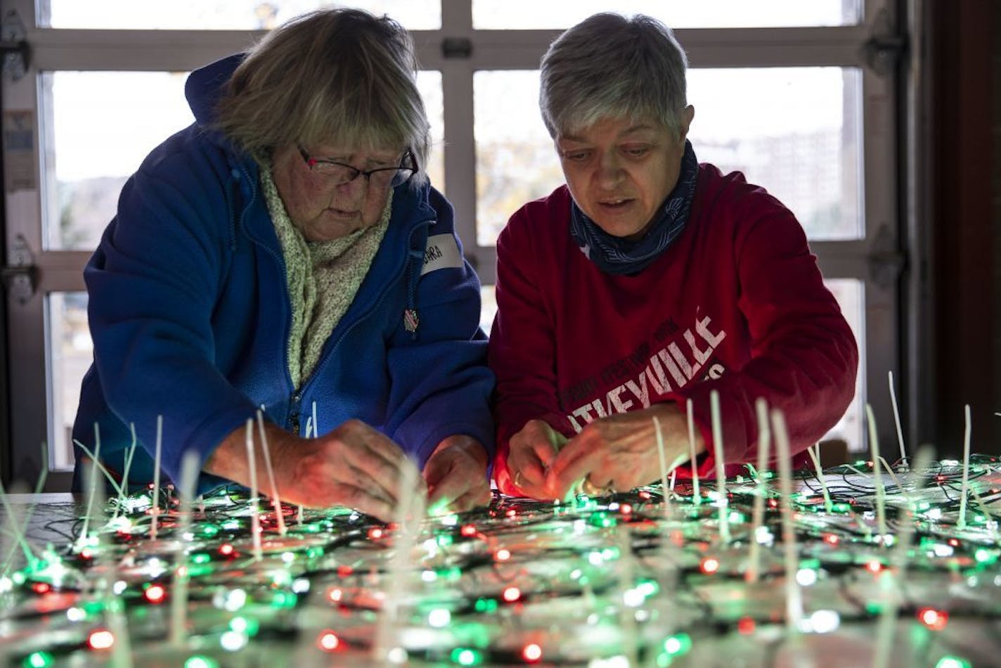 (Left) Barbara Long and Margy Fraboni worked on attaching Christmas lights to chicken wire that would eventually be attached to the exterior of the Bentleyville large Christmas tree.