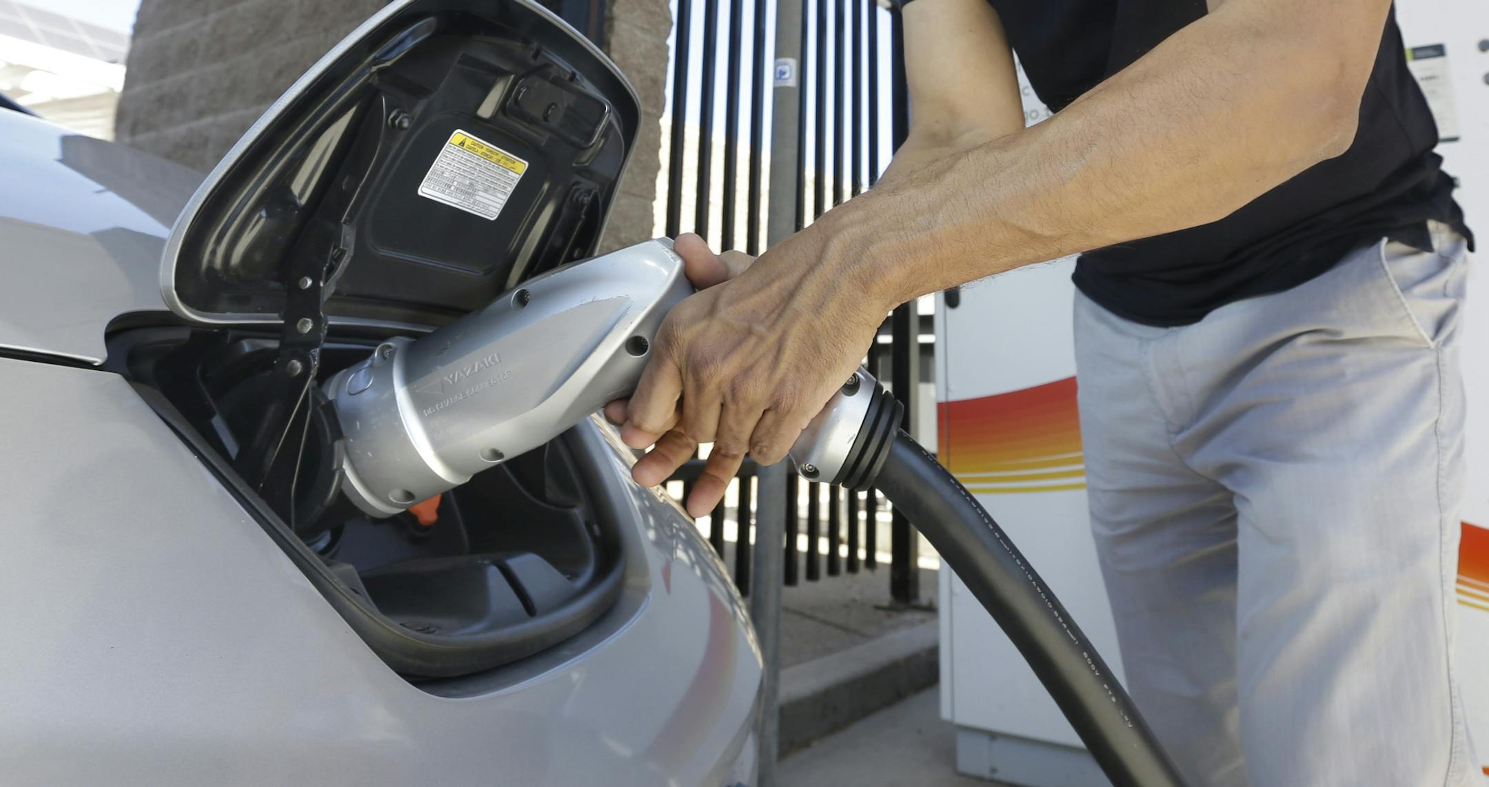 FILE - In this Thursday, Sept. 17, 2015 file photo, Darshan Brahmbhatt, plugs a charger into his electric vehicle at the Sacramento Municipal Utility District charging station in Sacramento, Calif. Calif., Gov Jerry Brown, on Friday, Jan. 26, 2018, issued and executive order outlining a plan to put 5 million zero-emission vehicles on California's roads by 2030. (AP Photo/Rich Pedroncelli, File)