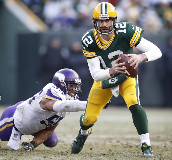 Green Bay Packers quarterback Aaron Rodgers (12) broke Minnesota Vikings outside linebacker Anthony Barr (55) tackle , and Everson Griffen and threw a