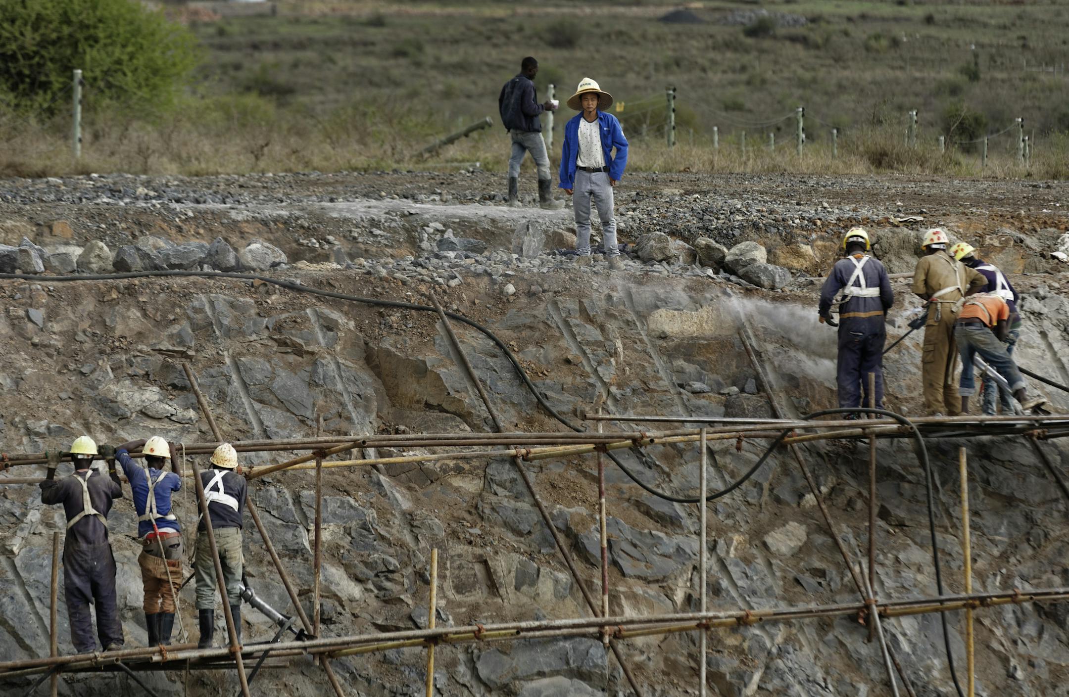 In this photo taken Wednesday, Nov. 23, 2016, a Chinese foreman supervises Kenyan laborers as they finish the sides of a cut of the Nairobi-Mombasa railway, leading to an existing bridge that goes across a corner of Nairobi National Park in Nairobi, Kenya. A controversial Chinese-built railway project involving an even larger 6km bridge that would go all the way over the beloved protected area in Kenya's capital has divided conservationists in this East African country. (AP Photo/Ben Curtis) ORG