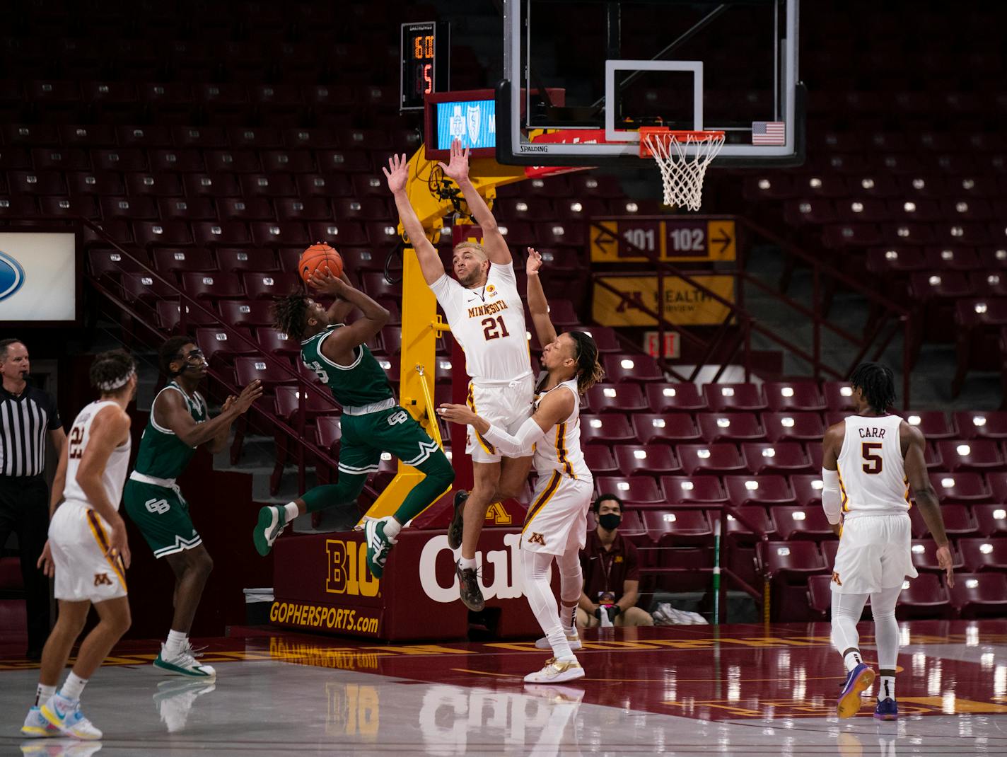 The Gophers' Jarvis Omersa (21) and Brandon Johnson (23) defended UW-Green Bay's P.J. Pipes as he shot in the first half.