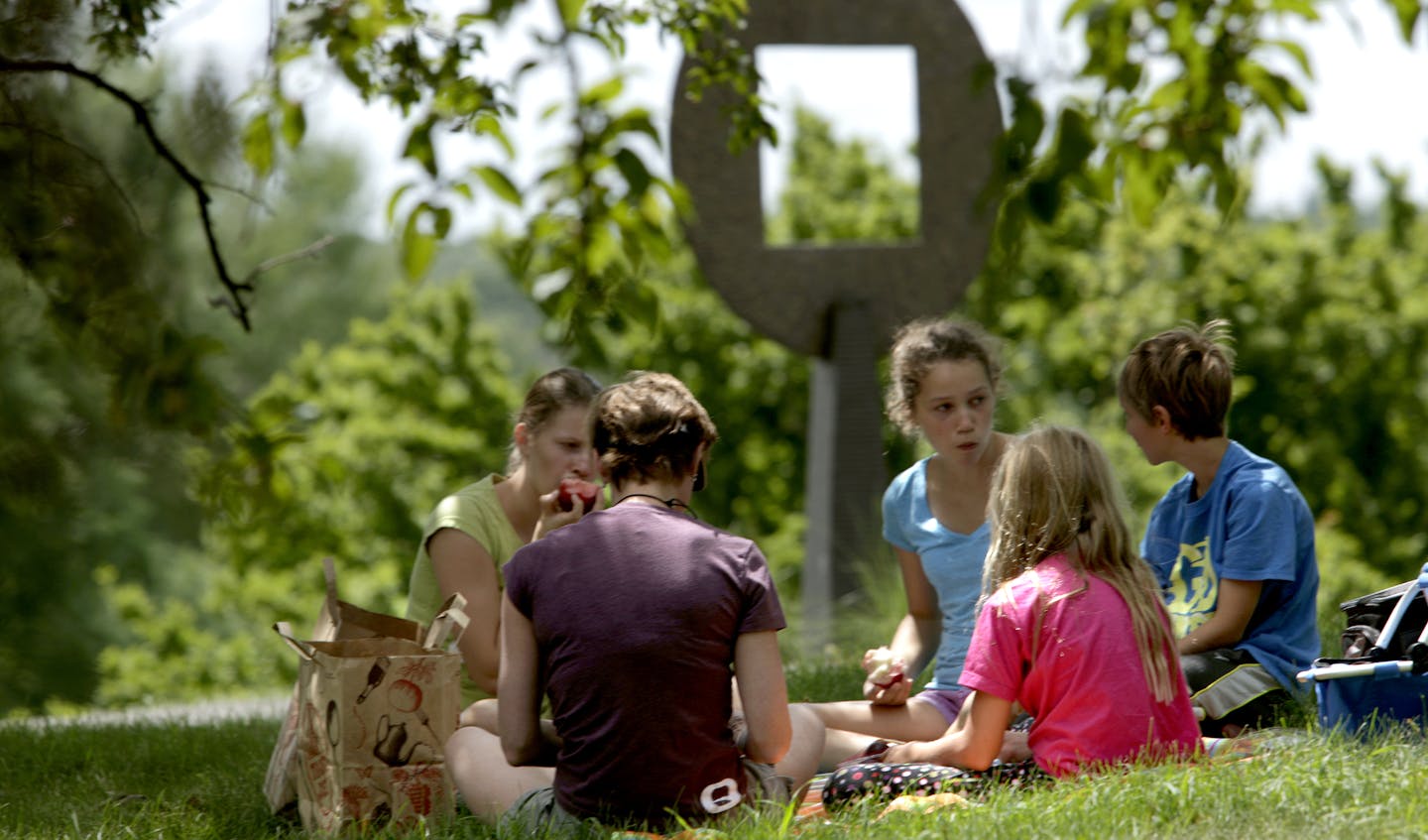 Leslie Johnson (brown shirt) said, "This is where my husband proposed to me. We bring our friends and family to out here to the same spot." Leslie Johnson (brown shirt), daughter Sophia, son Charlie of St. Louis Park and Emily Johnson (blue shirt), and Anna Johnson from Portsmith, New Hampshire had a picnic under the trees at the scupture garden with "DISC SPIRAL" 2000 by Jesus Bautista Moroles in the background at the University of Minnesota Landscape Arboretum in Chanhassen, MN on July 29, 201