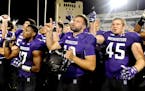 Northwestern cornerback Marcus McShepard (17), quarterback Zack Oliver (10) and linebacker Nathan Fox (45) sing the school song with fans at the end o