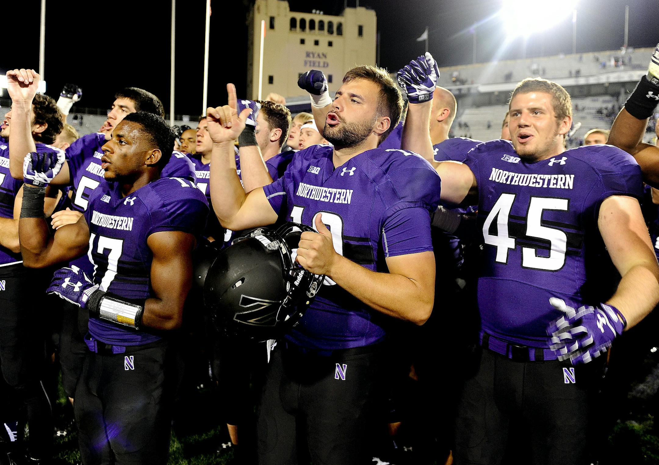 Northwestern cornerback Marcus McShepard (17), quarterback Zack Oliver (10) and linebacker Nathan Fox (45) sing the school song with fans at the end of an NCAA college football game against Ball State, Saturday, Sept. 26, 2015, in Evanston, Ill. Northwestern won 24-19. (AP Photo/Matt Marton)