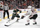 Minnesota Wild defenseman Matt Dumba (24) passed the puck down the ice while being defended by Chicago Blackhawks left wing Brandon Saad (20) in the f