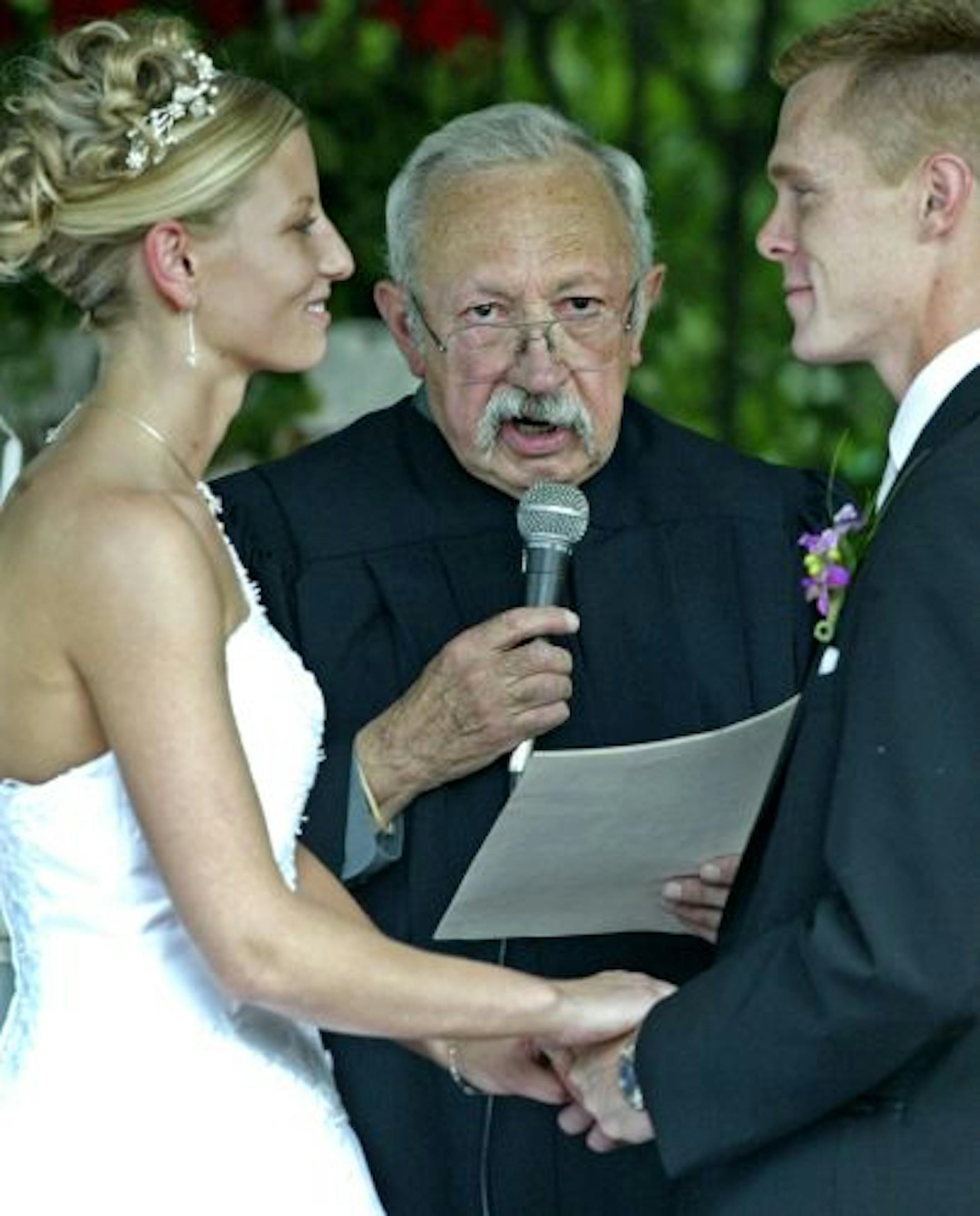 Judge Albertson conducts wedding vows between Michelle Harris and husband Bryce Harris during a recent outdoor ceremony.