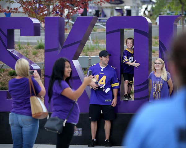 Minnesota Vikings fans pose for photos by a large Skol sign before the start of a Vikings and Jacksonville Jaguars joint practice session Thursday, Au