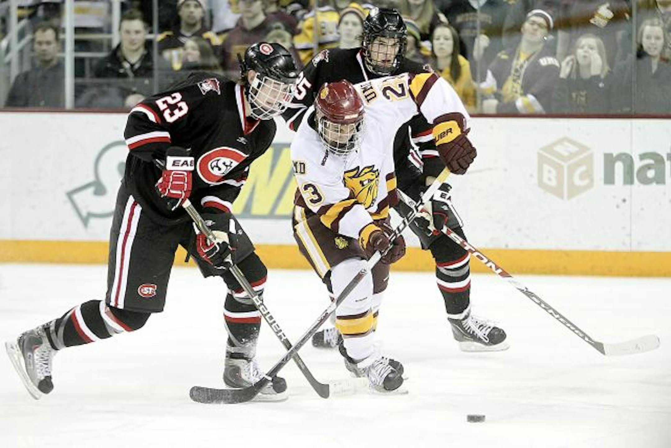 Minnesota Duluth's J.T. Brown (23) skates for the puck with St. Cloud State's Cam Reid (23) and Oliver Lauridsen (25) during an NCAA college hockey game on Saturday, Feb. 12, 2011, in Duluth, Minn.