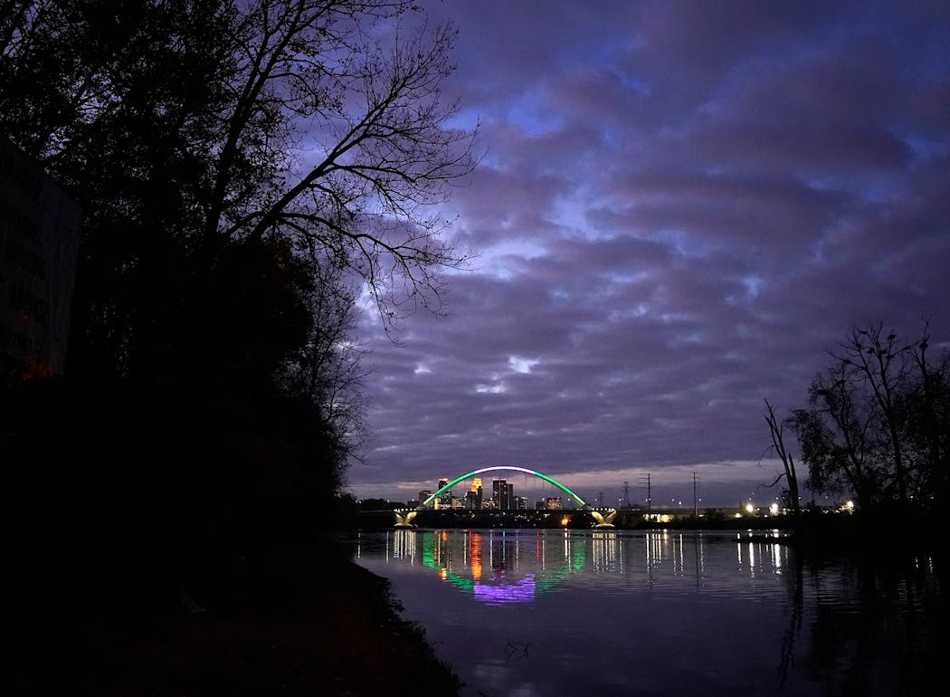 Dawn breaks on the Mississippi River the morning after near Marshall Terrace Park as light from the nearby Lowry Avenue Bridge and the Minneapolis skyline is reflected in the water Nov. 3, 2021.