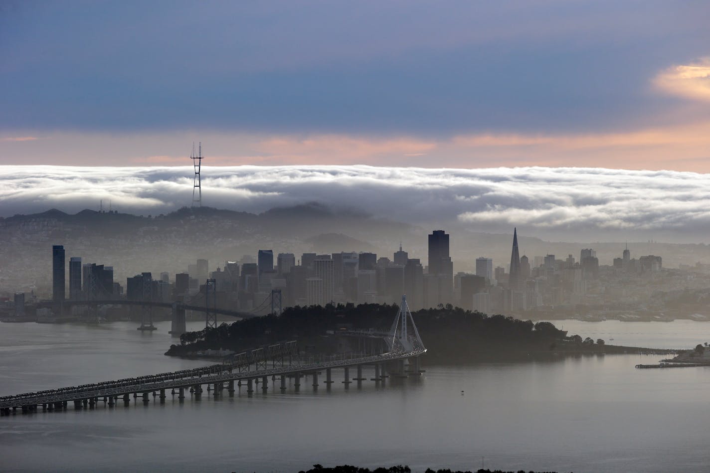 A blanket of fog covers the San Francisco skyline in a view from the Berkeley Hills. If just three big cities — New York, San Francisco and San Jose — relaxed planning rules, the Economist writes, America's GDP could be 4% higher.