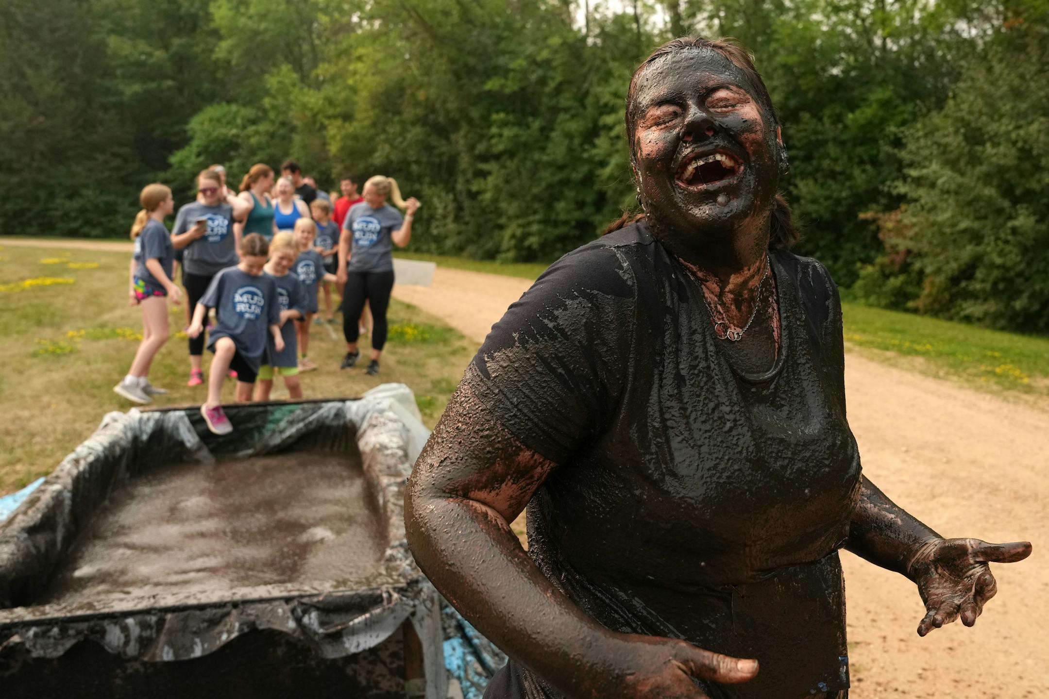 Shannon Olsen of Blaine laughs as she wipes mud from her face after going all in the first of the mud pits during the Minneswashta Mud Run.