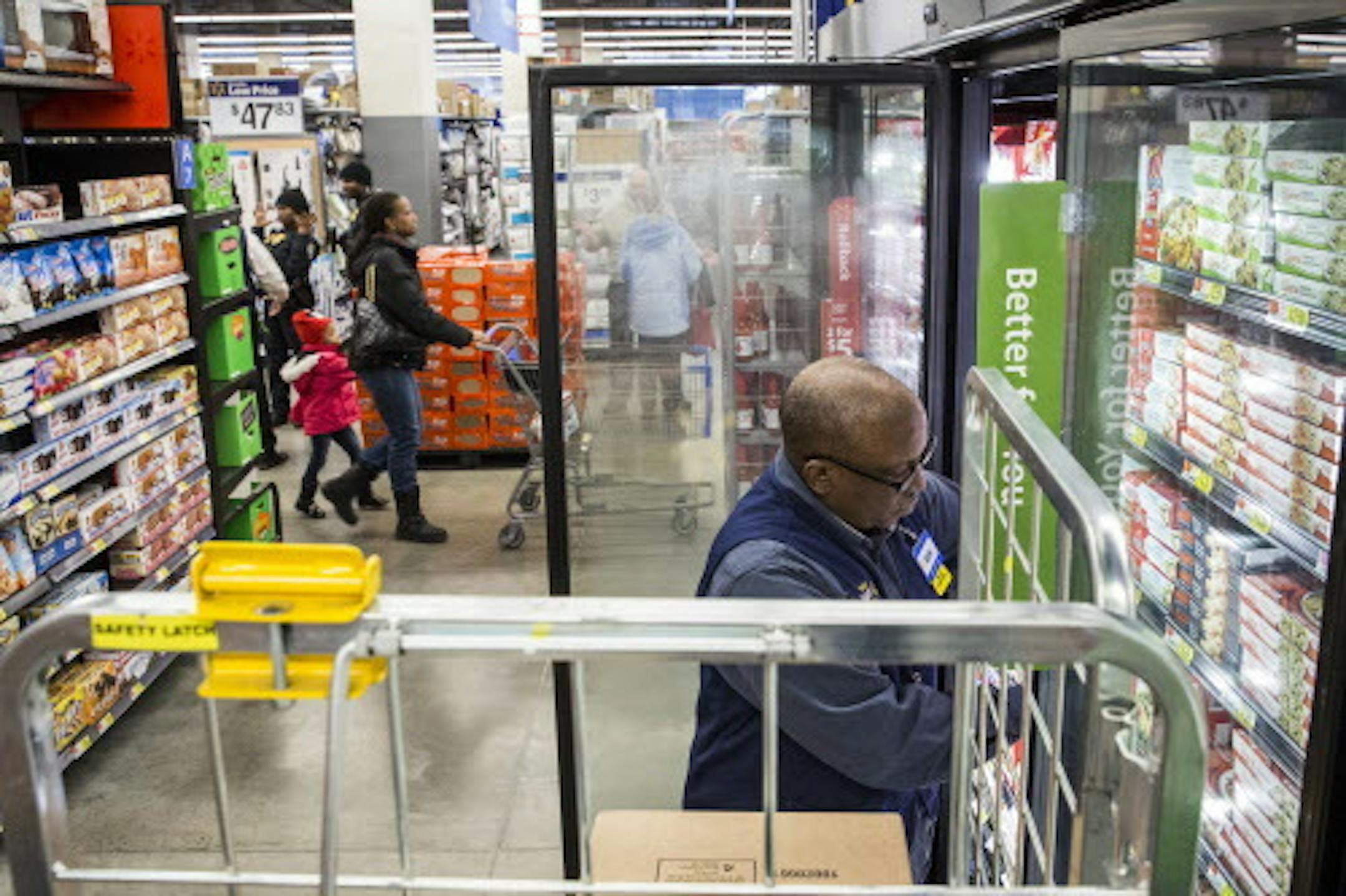 Walmart employee Kevin James restocks in the frozen foods aisle at a store in Washington, Feb. 19, 2015. Walmart, the largest private employer in the country, said on Thursday that it would increase wages for a half-million employees. (Drew Angerer/The New York Times)