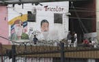 Youth hang out next to a mural featuring the late President Hugo Chavez and his successor Nicolas Madro, at the Petare shantytown, in Caracas, Venezue