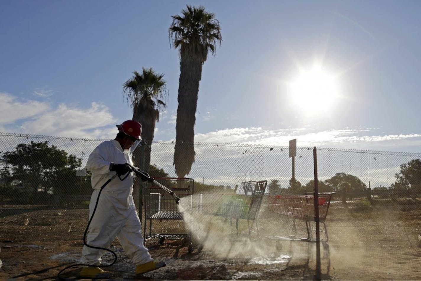 In this Sept. 25, 2017 photo, a worker sprays a bleach solution on a sidewalk in downtown San Diego as part of an effort to control a deadly hepatitis A outbreak. The increased number of hepatitis cases in the homeless population, and the geographic spread of the disease led California to declare a state of emergency in October.