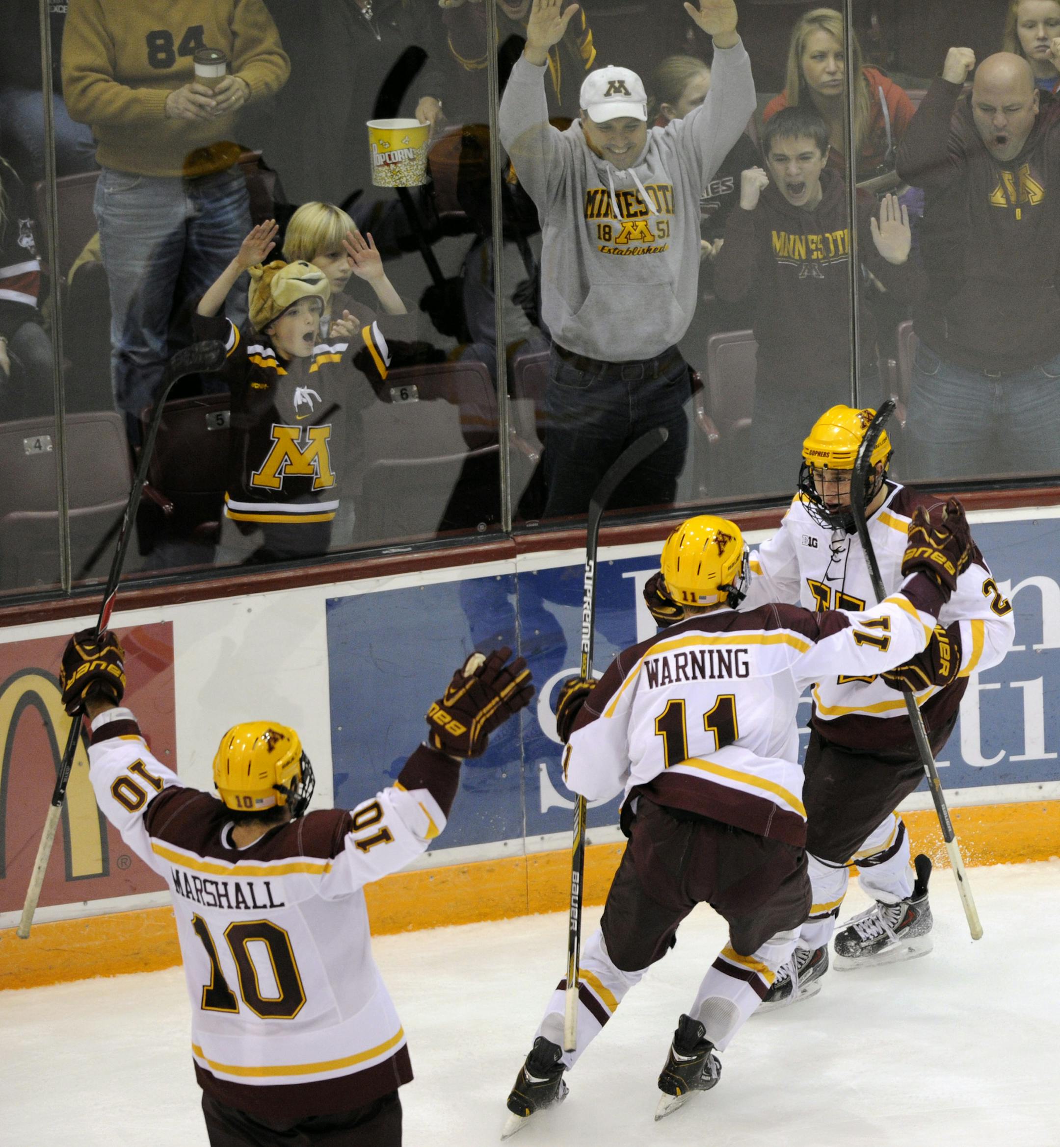 Minnesota defense Ben Marshall (10), forward Sam Warning (11) and forward Justin Kloos celebrate a goal by Kloos in overtime to end an NCAA college hockey game against St. Cloud State, Saturday, Nov. 1, 2014, in Minneapolis. Minnesota won 4-3 in overtime. (AP Photo/Hannah Foslien)