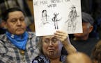 Lisa Anderson, a member of the Chumash-Ohlone tribe, holds a sign favoring divestment before a Seattle City Council meeting Tuesday, Feb. 7, 2017, in 